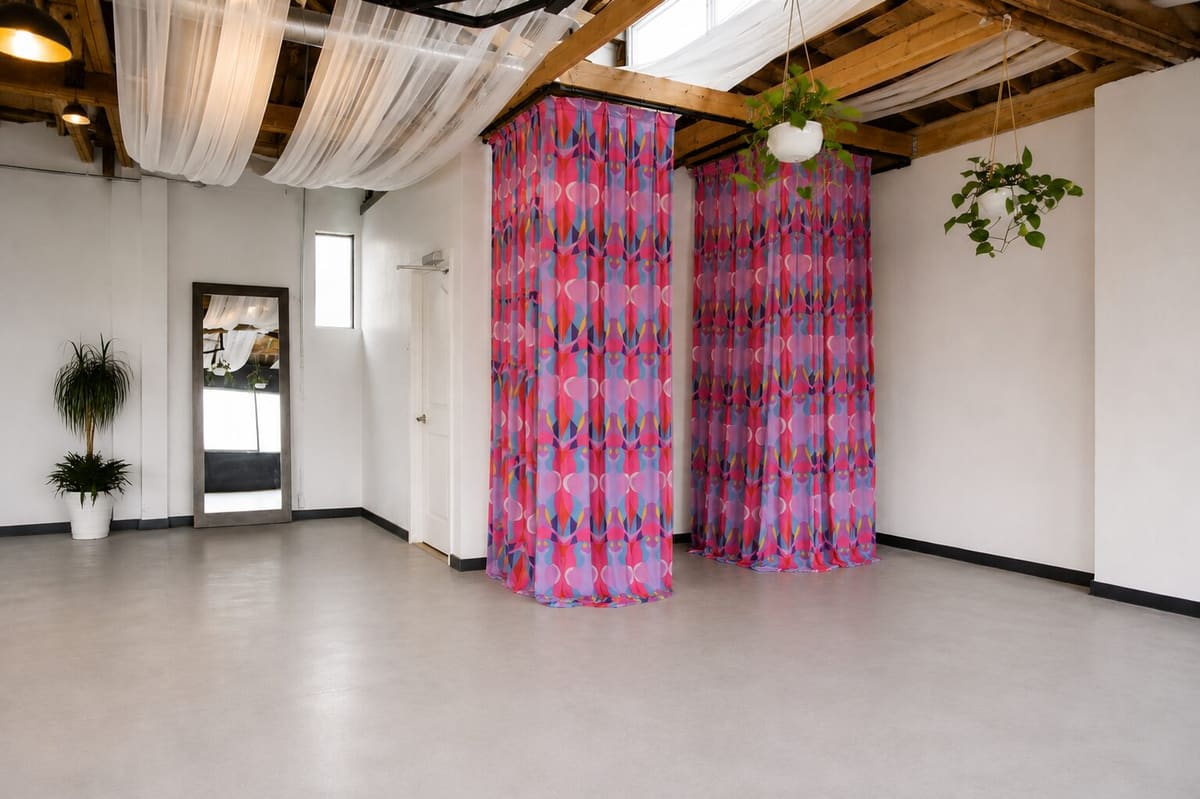 Two curtained changing areas with patterned pink curtains, a full-length mirror and plants